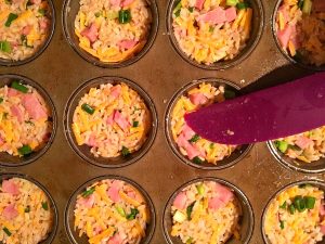 ham and rice mixture being pressured into muffin tin