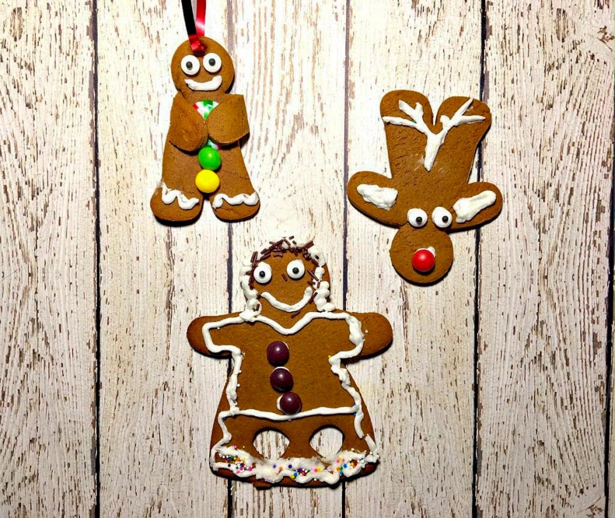 3 gingerbread cookies (a reindeer, dancing gingerbread girl and a gingerbread man) on a white faux wooden surface