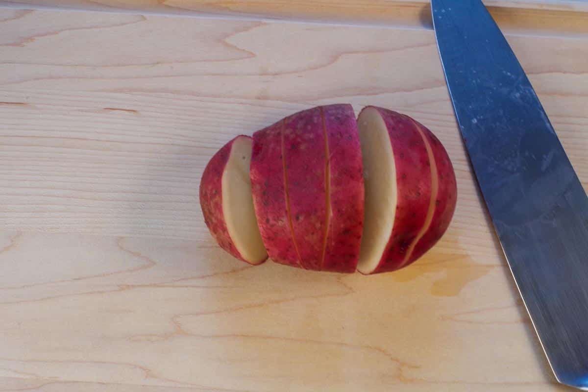 potato with 5 cuts in it on cutting board