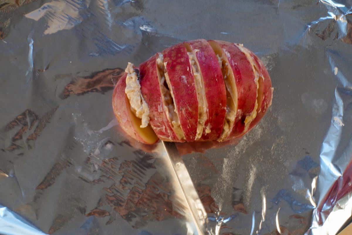 sliced potato on foil with mix being added between slices