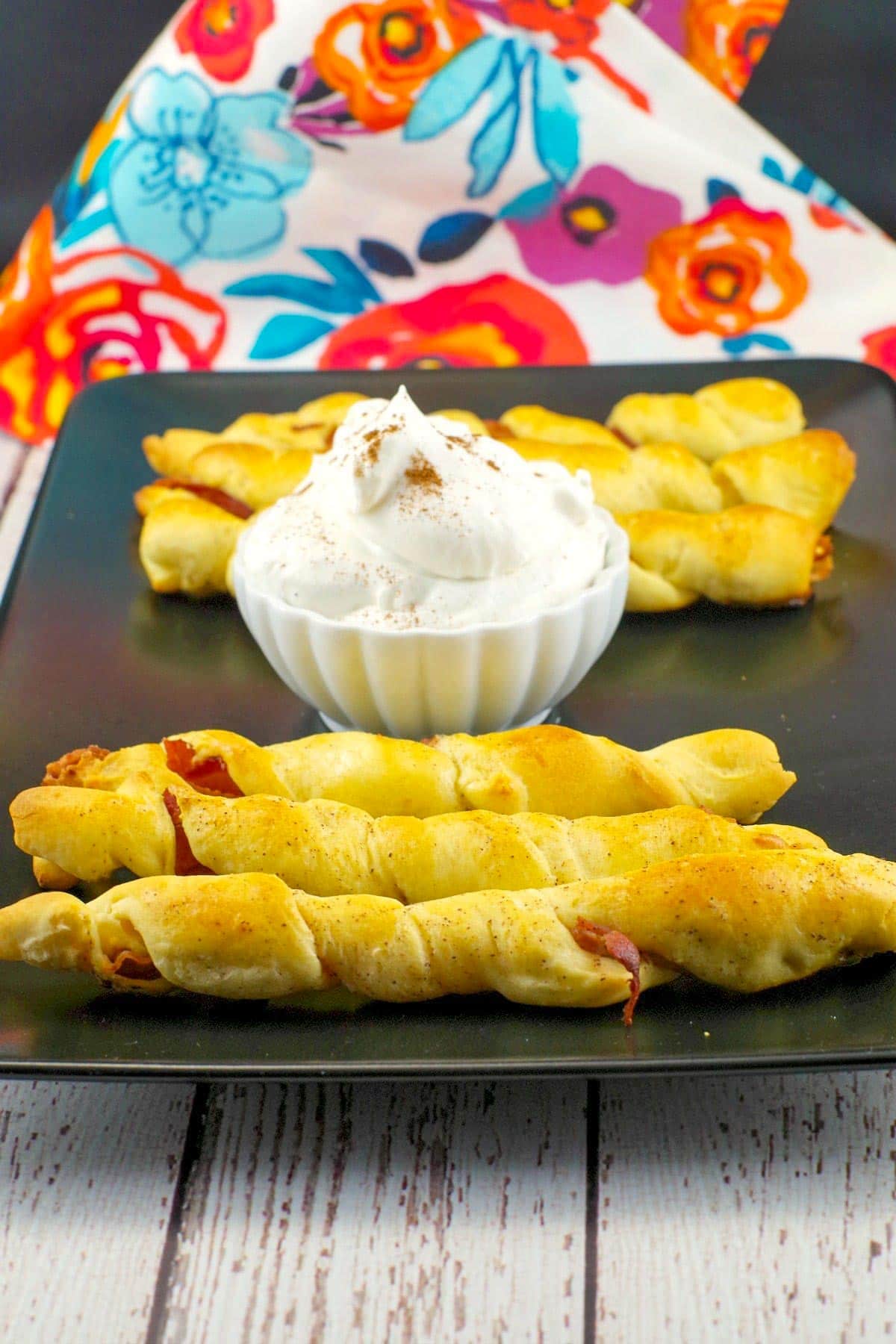 Pigs in a blanket breakfast on black tray with dip in the middle 