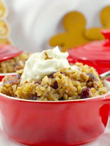 cranberry gingerbread rice pudding in a red bowl with gingerbread men and more red bowls in background