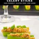 Pinterest Pin with white text on black background on top and bottom and photo of 2 buffalo chicken celery sticks in foreground and stem of wine glass and black tray of celery sticks in background