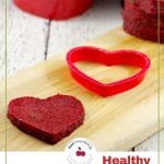 Pinterest pin with red and black text on white on bottom and photo of healthy jello hearts on wooden cutting board
