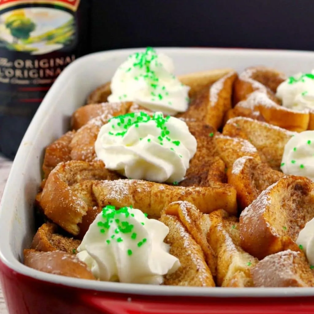 bailey's French Toast Casserole in white and orange dish with bottle of Bailey's Irish Cream in the background