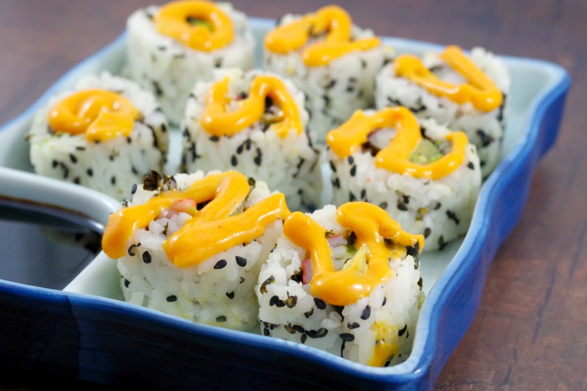 9 california rolls in a sushi dish with sriracha mayonnaise swirled on top