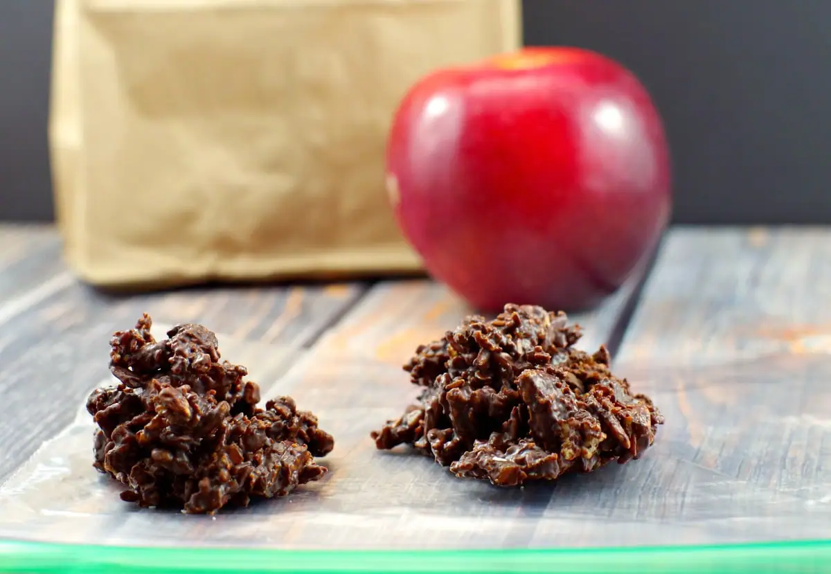 2 chocolate clusters on a ziploc bag with an apple and brown paper lunch bag in the background