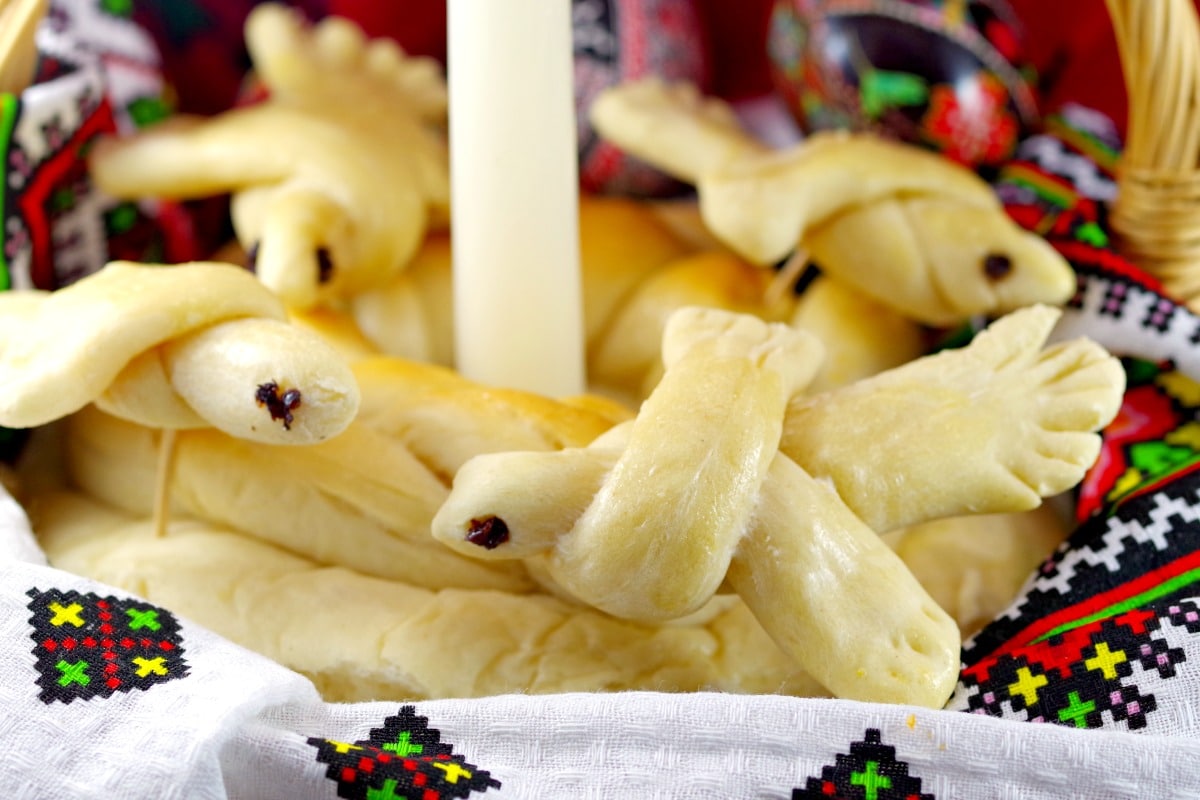 Ukrainian Easter Doves made of bread decorating a loaf of paska in basket (with candle in the middle)
