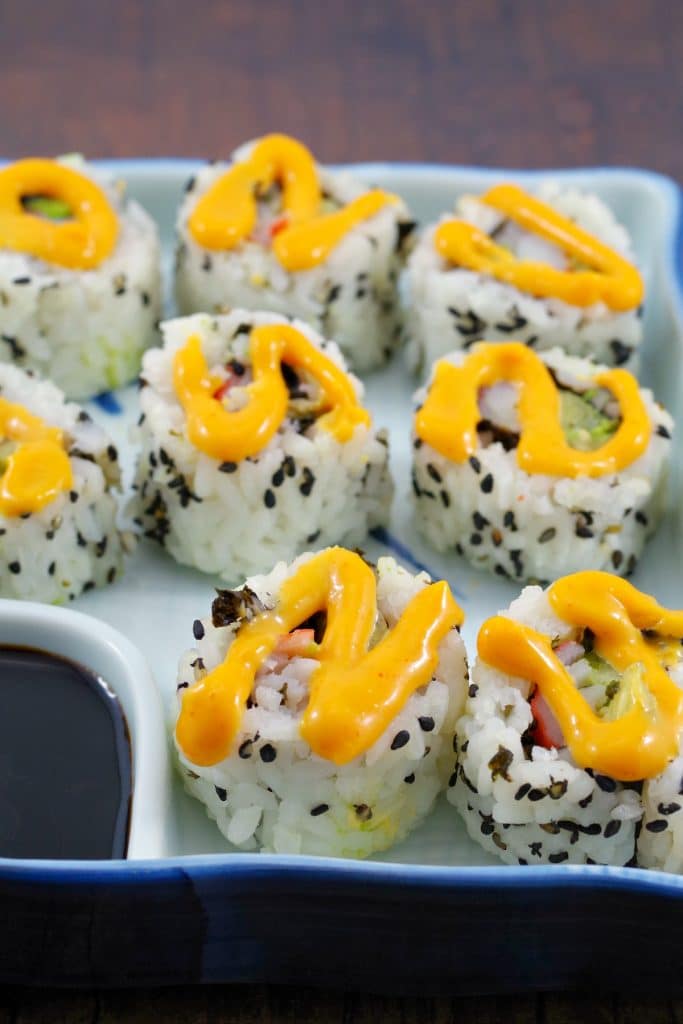 9 california rolls in a sushi dish with sriracha mayonnaise swirled on top