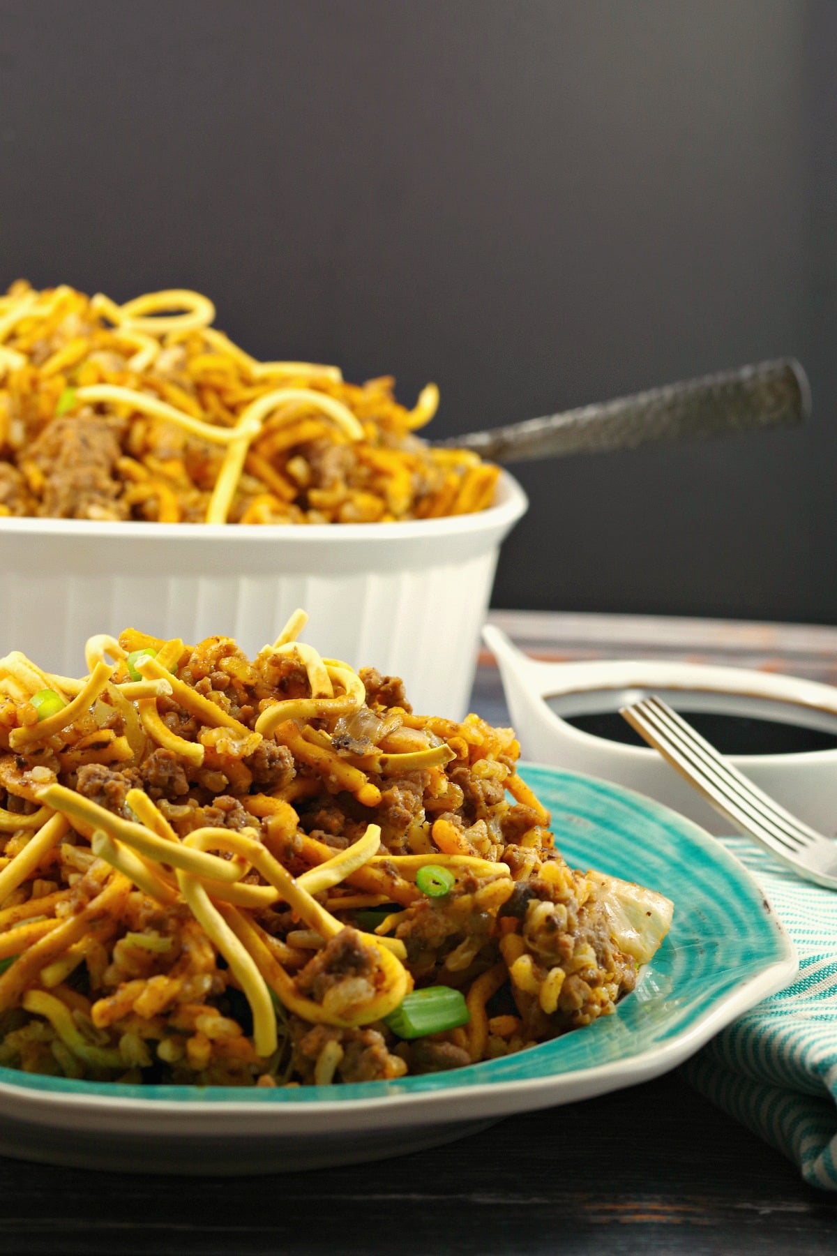 Chow Mein Hotdish casserole on a plate in front with casserole dish in background