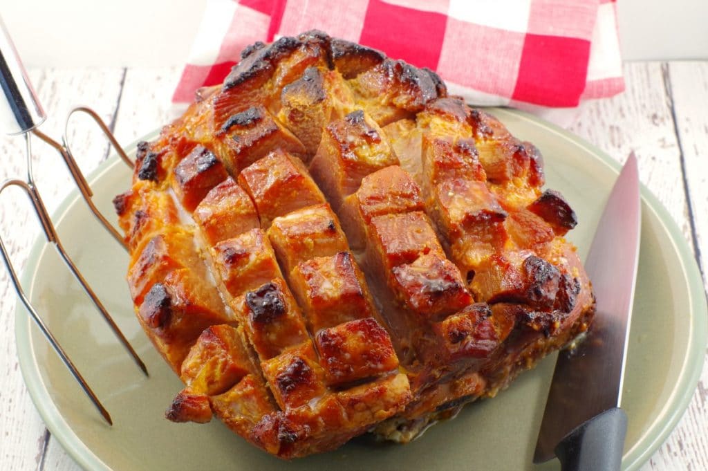 Whole, scored and cooked picnic ham on a plate