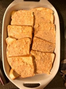 bread overlapping in two rows in casserole dish, covered with half of the mixture