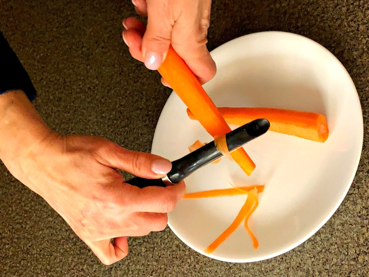 carrot being ribboned with vegetable peeler