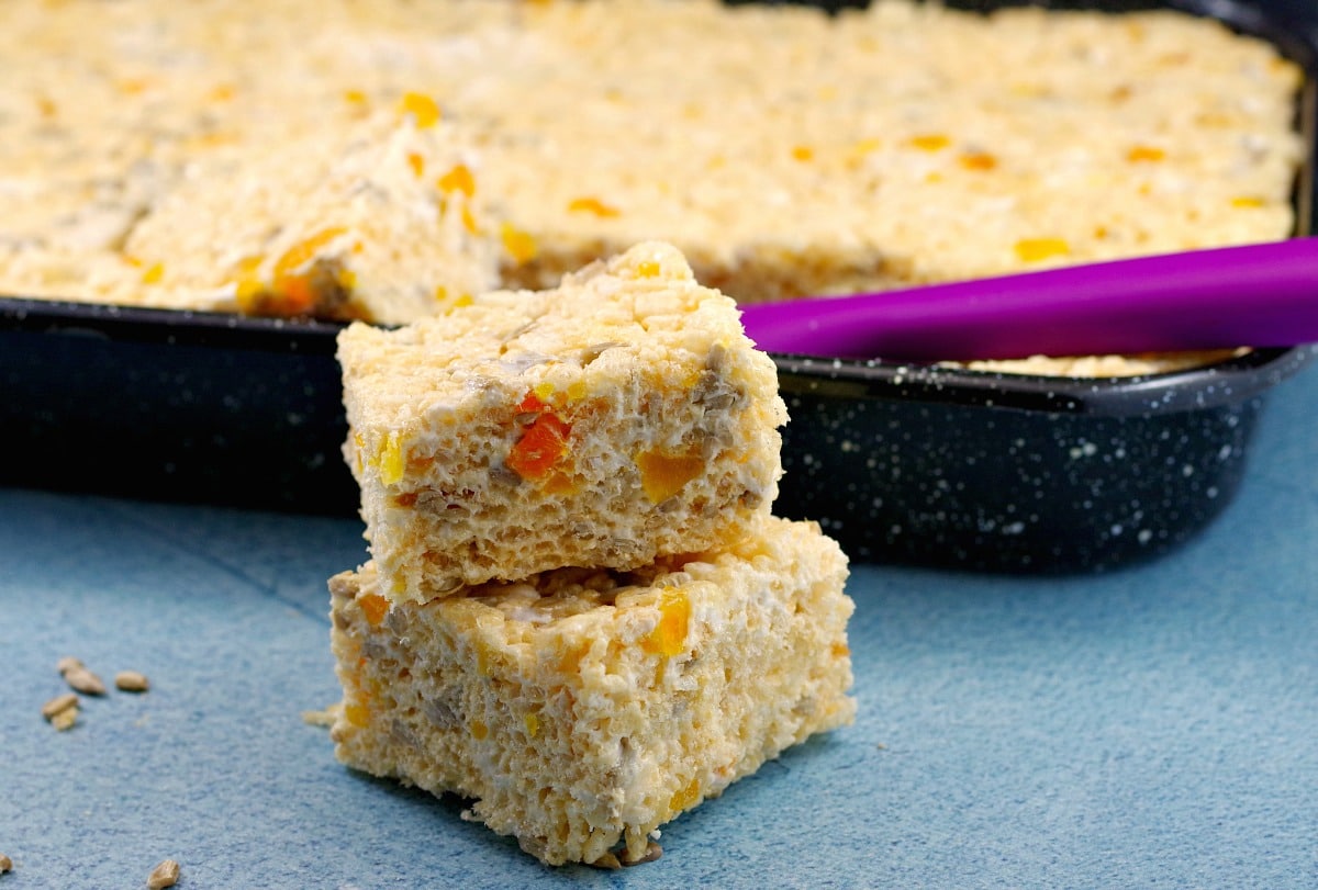 2 Rice Crispy Treats stacked in front of a pan of rice crispy treats