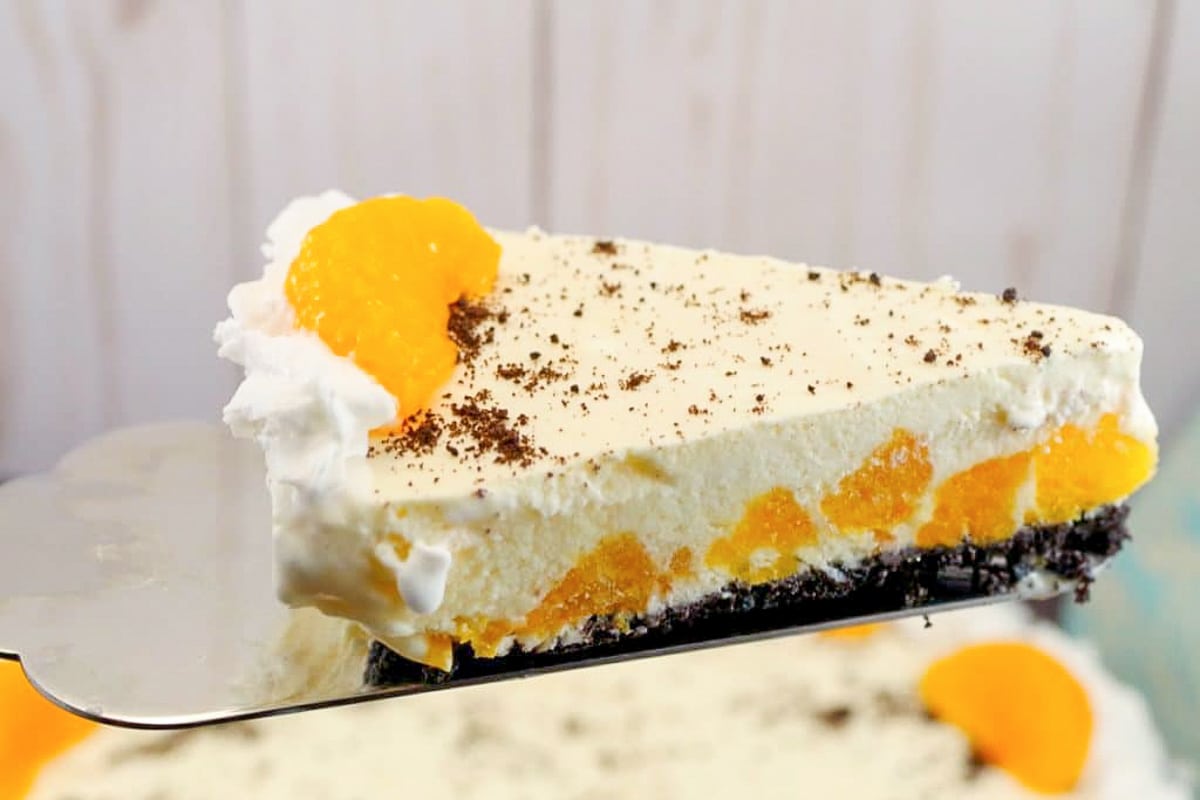 Piece of Dairy-free Orange Dreamsicle Pie being lift out of whole pie with metal pie lifter