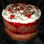 Easy Black Forest Trifle in a clear glass trifle bowl with a black cloth background