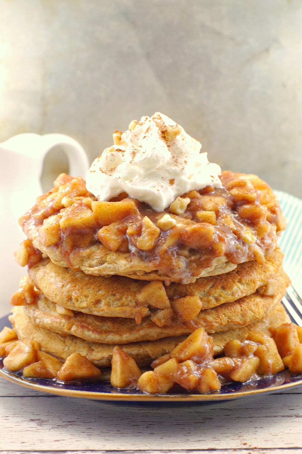 stacked pancakes with apple topping and whipped cream