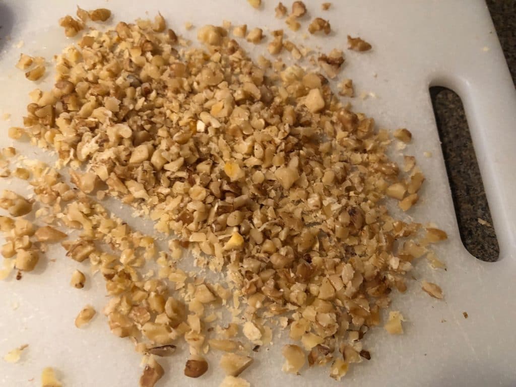 walnuts chopped finely on white cutting board