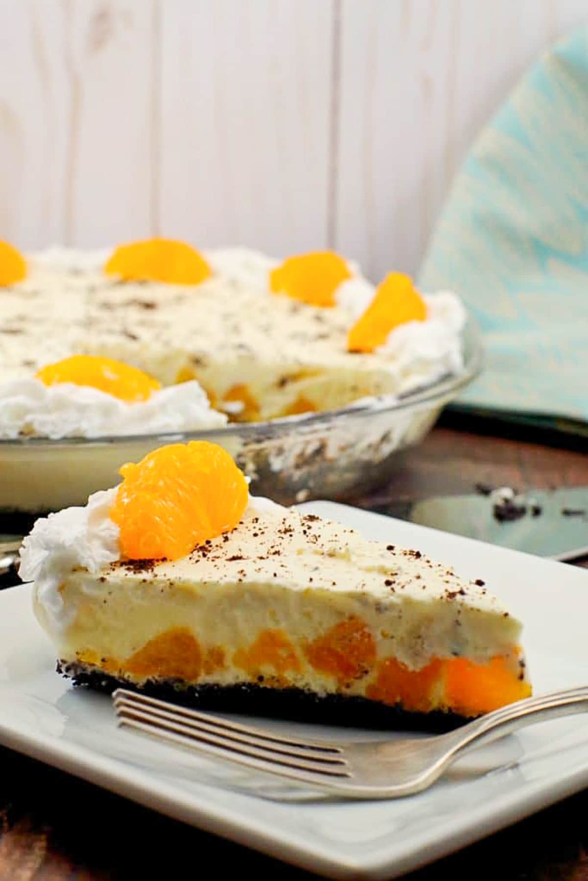 Piece of Orange Creamsicle pie (dairy-free) on white plate with whole pie in background
