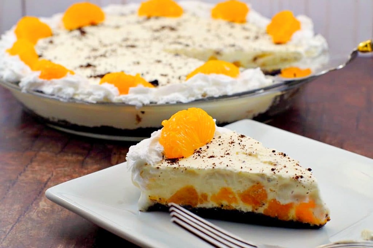 Piece of Orange Creamsicle pie (dairy-free) on white plate with whole pie in background