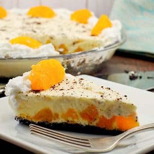 Piece of Orange Creamsicle pie (dairy-free) on white plate with whole pie in background