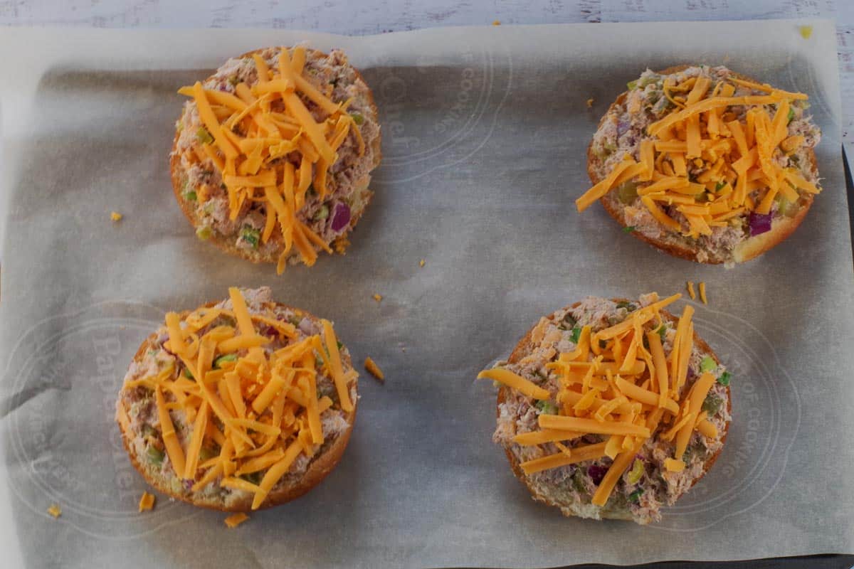 cheese sprinkled on top of tuna melts on parchment lined baking sheets