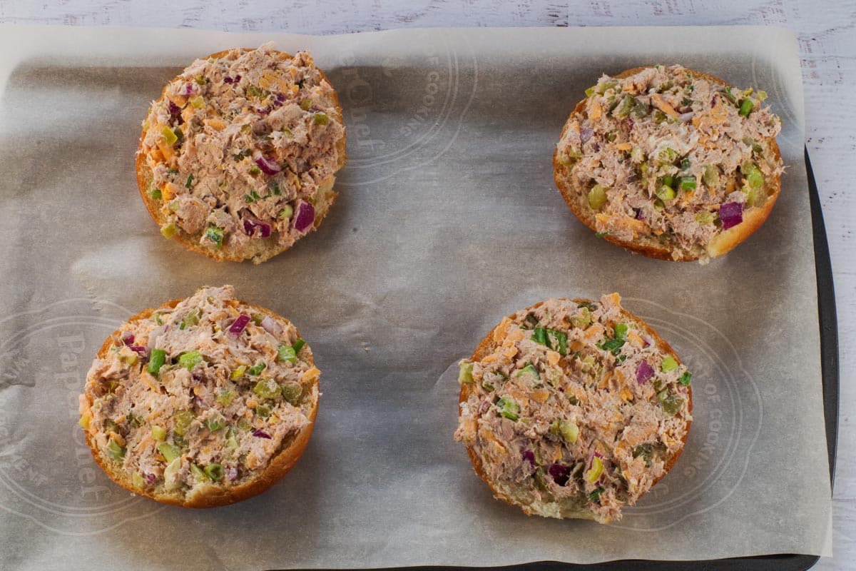 Buns topped with Tuna melt mixture on parchment lined baking sheet