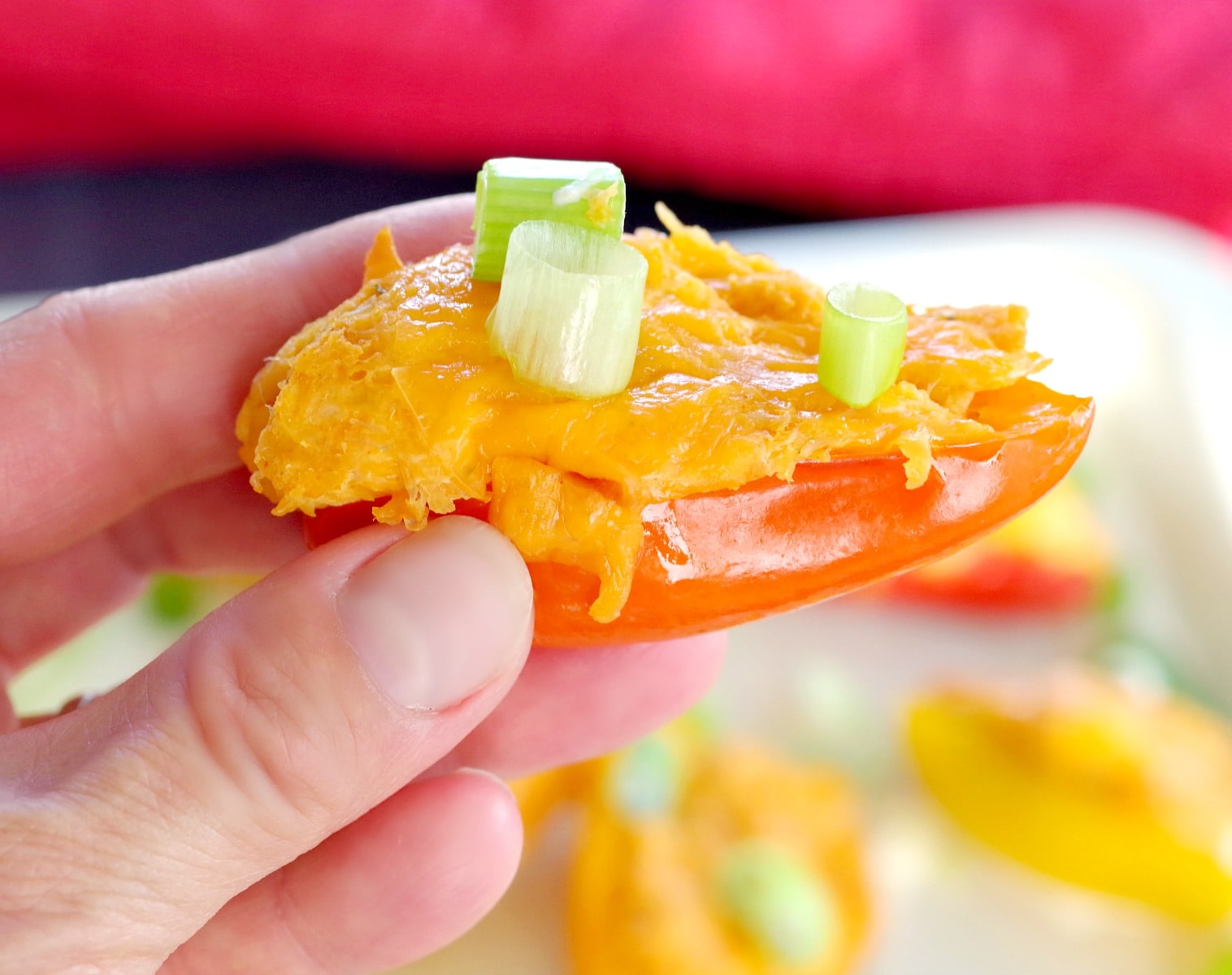 buffalo chicken stuffed mini pepper being held up between thumb and fingers
