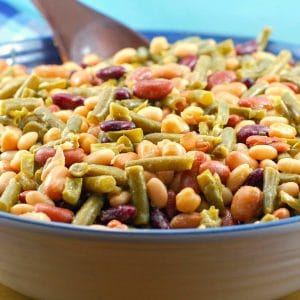 Easy (vegan) mixed bean salad in a large bowl with a dark brown wooden spoon