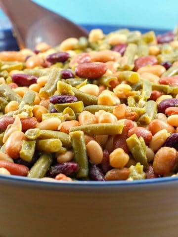 Easy (vegan) mixed bean salad in a large bowl with a dark brown wooden spoon