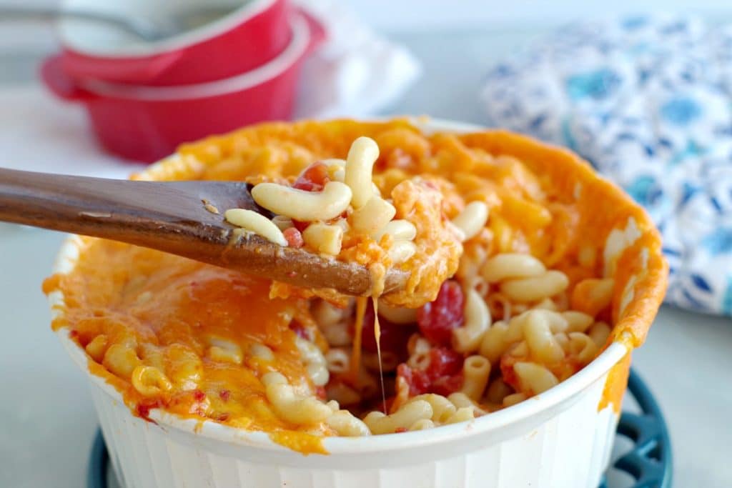Mac and Cheese in a white casserole bowl with wooden spoon scooping it out