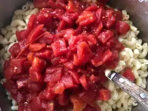 Tomatoes being added to macaroni