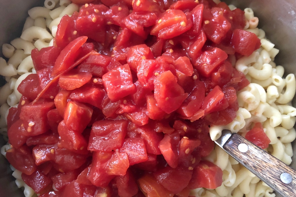 Tomatoes being added to macaroni