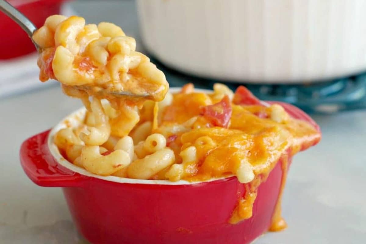 Mac and Cheese with tomatoes being lifted out of red bowl with spoon