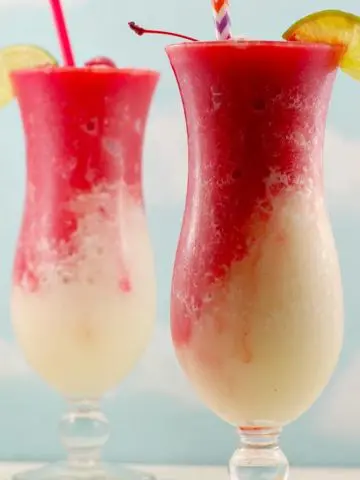 2 Miami Vice drinks on white wooden surface with a blue sky background