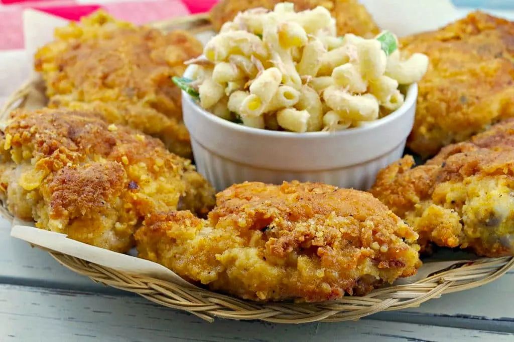 Fried chicken on a plate with bowl of macaroni salad in the middle