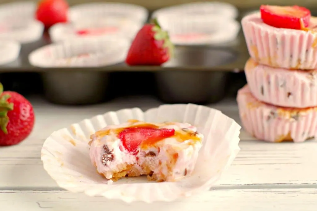 Strawberry Drumstick frozen yogurt cup that's been bit into on wrapper with muffin pan in background