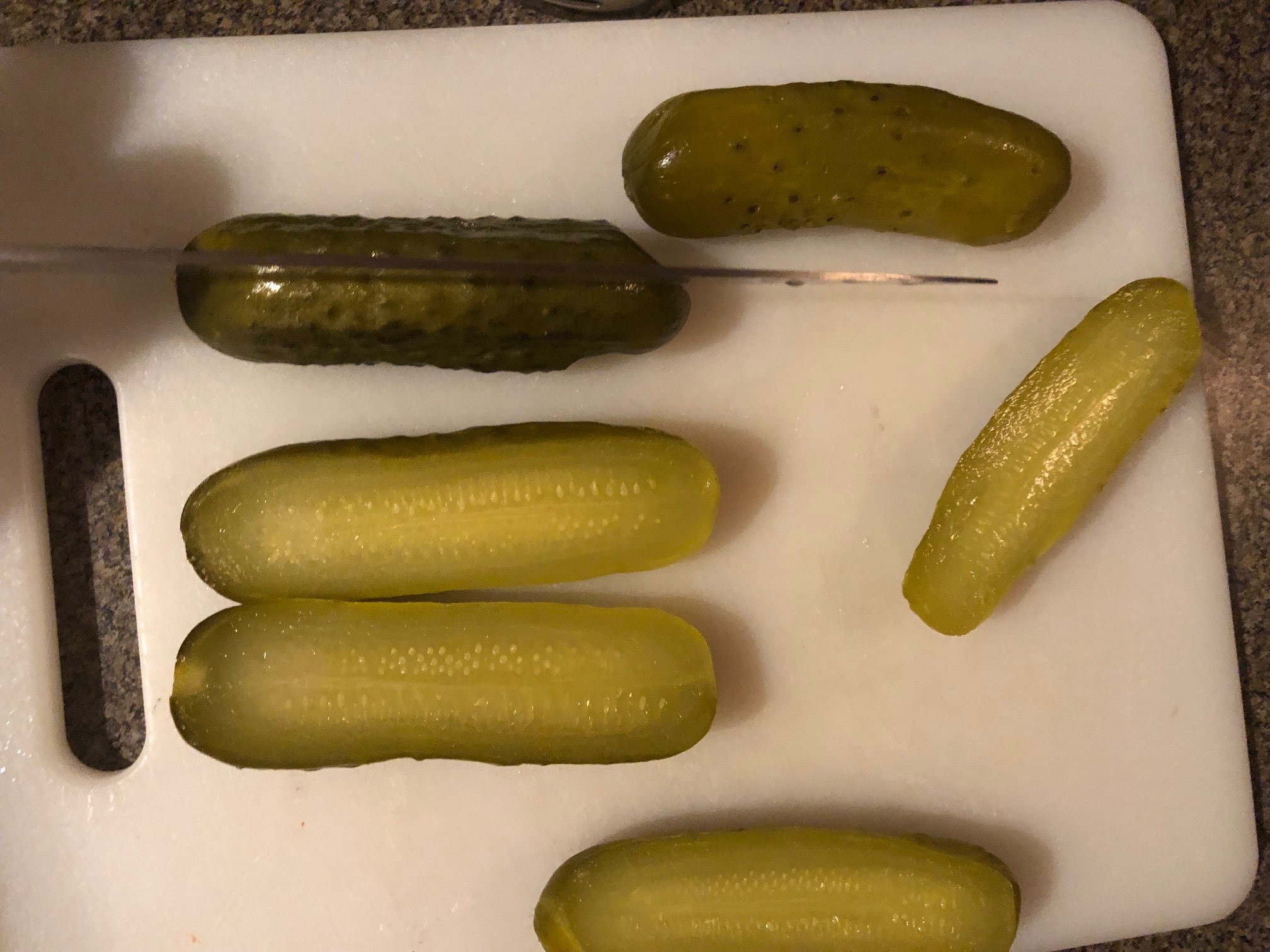 Pickles being sliced in half, lengthwise