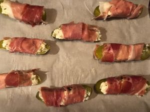 Prosciutto wrapped pickles on parchment lined baking sheet