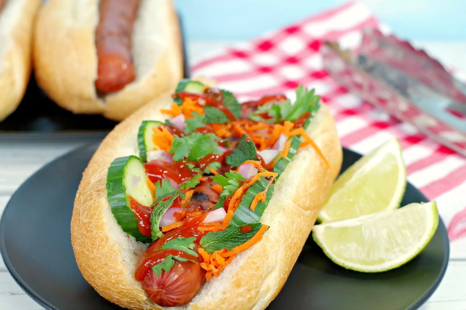 Banh Mi turkey hot dog on black plate with lime wedges