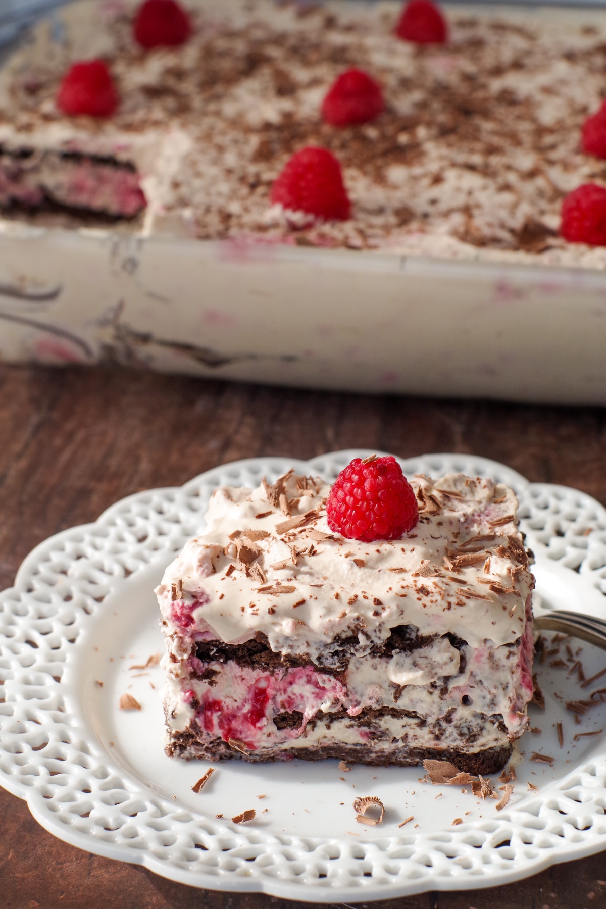 raspberry dulce de leche icebox cake on white plate with glass dish of cake in the background