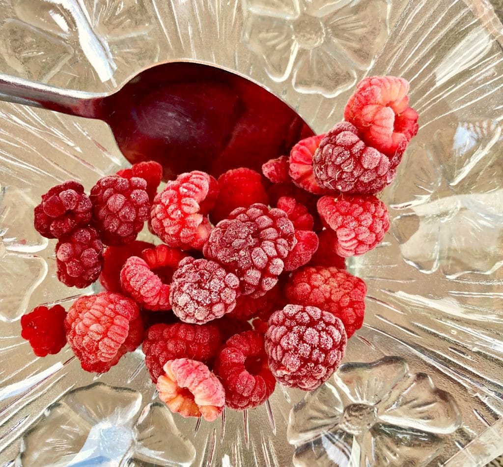 frozen raspberries in glass bowl with spoon