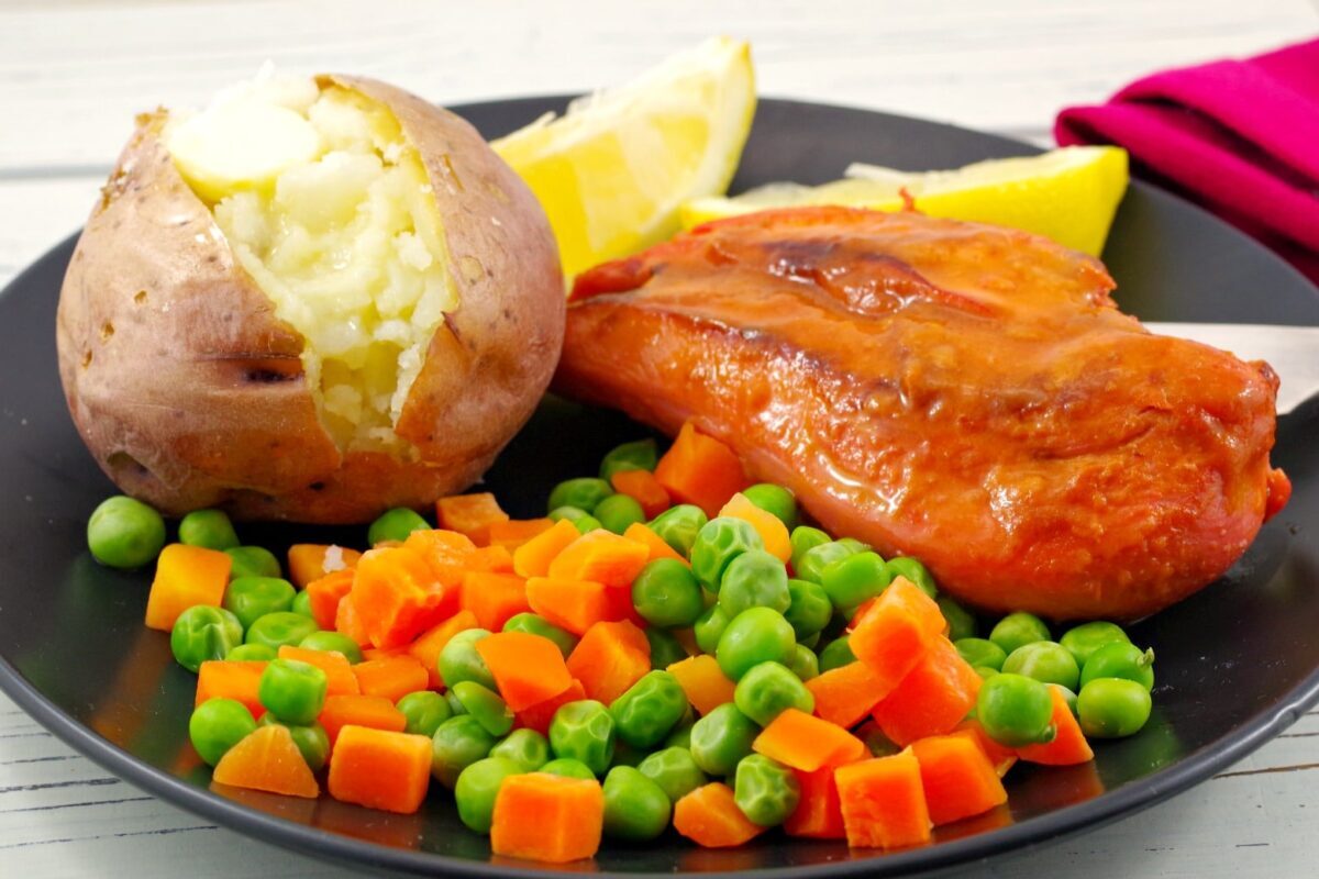 Monterey chicken on plate with baked potato and mixed vegetable