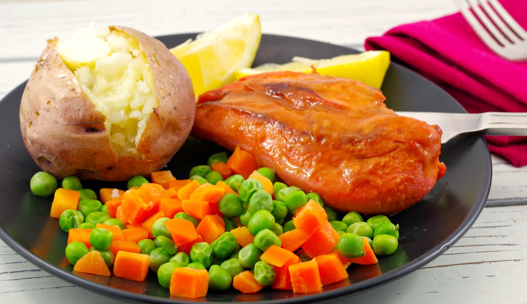 Monterey chicken on plate with baked potato and mixed vegetable