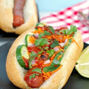 Banh Mi turkey hot dog on black plate with lime wedges