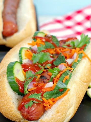 Banh Mi turkey hot dog on black plate with lime wedges
