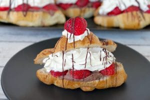 Strawberry Tiramisu eclair on black plate with eclairs in the background