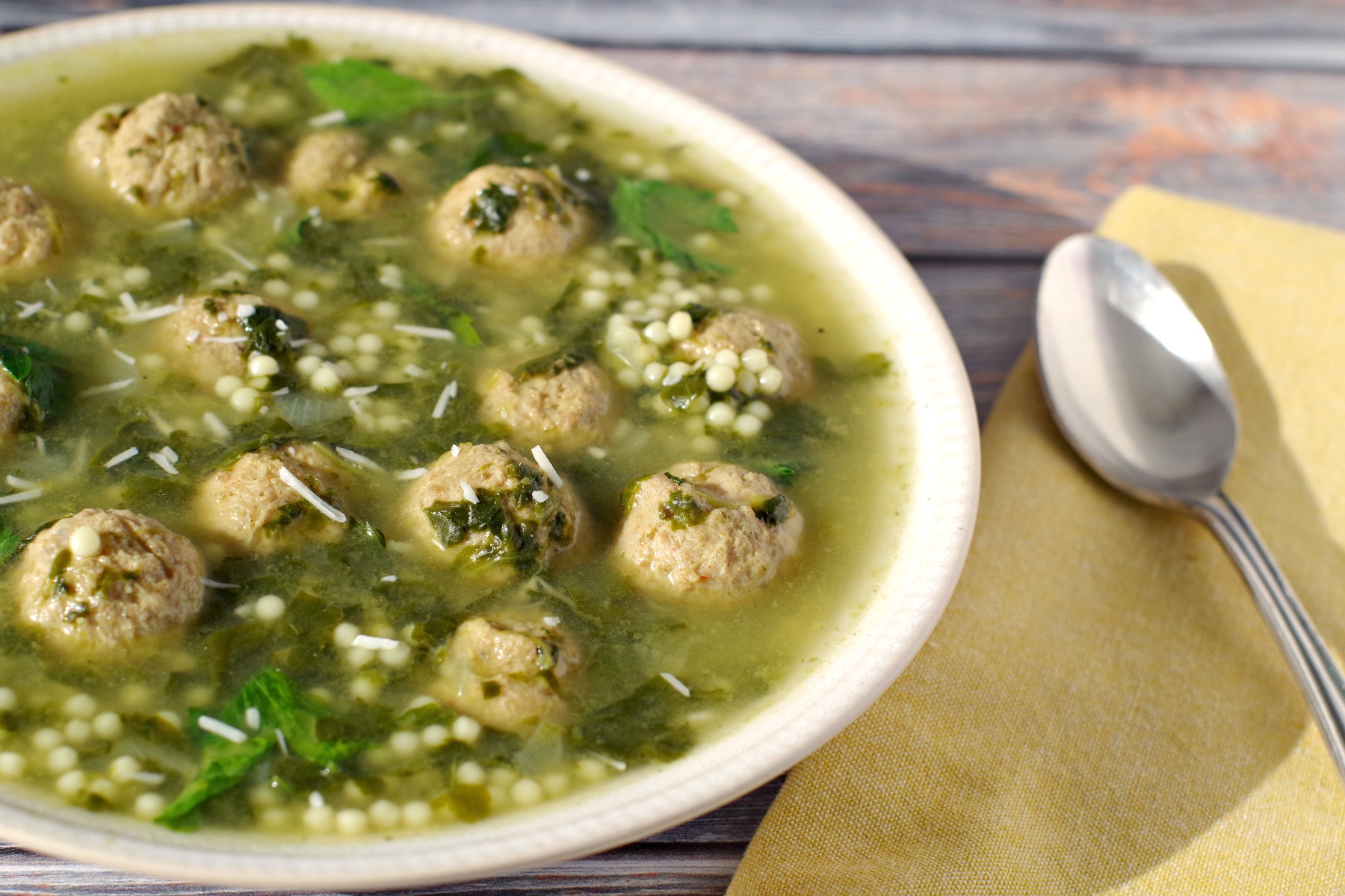 Easy Italian Wedding soup in beige bowl with yellow napkin