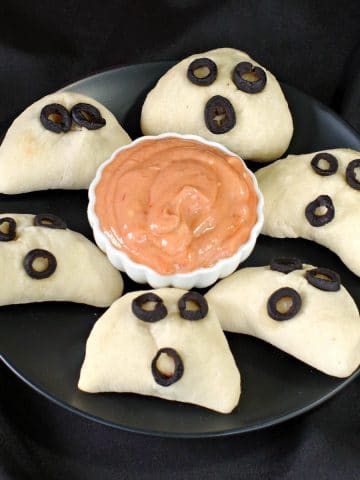 phantom pierogies on a black plate with dip in the middle