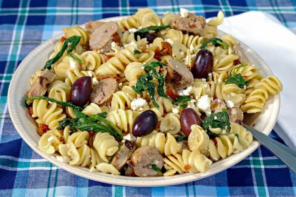 Greek pasta in a blue bowl with a brown wooden spoon
